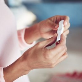 Woman looking at a pregnancy test wondering "Am I Pregnant?"