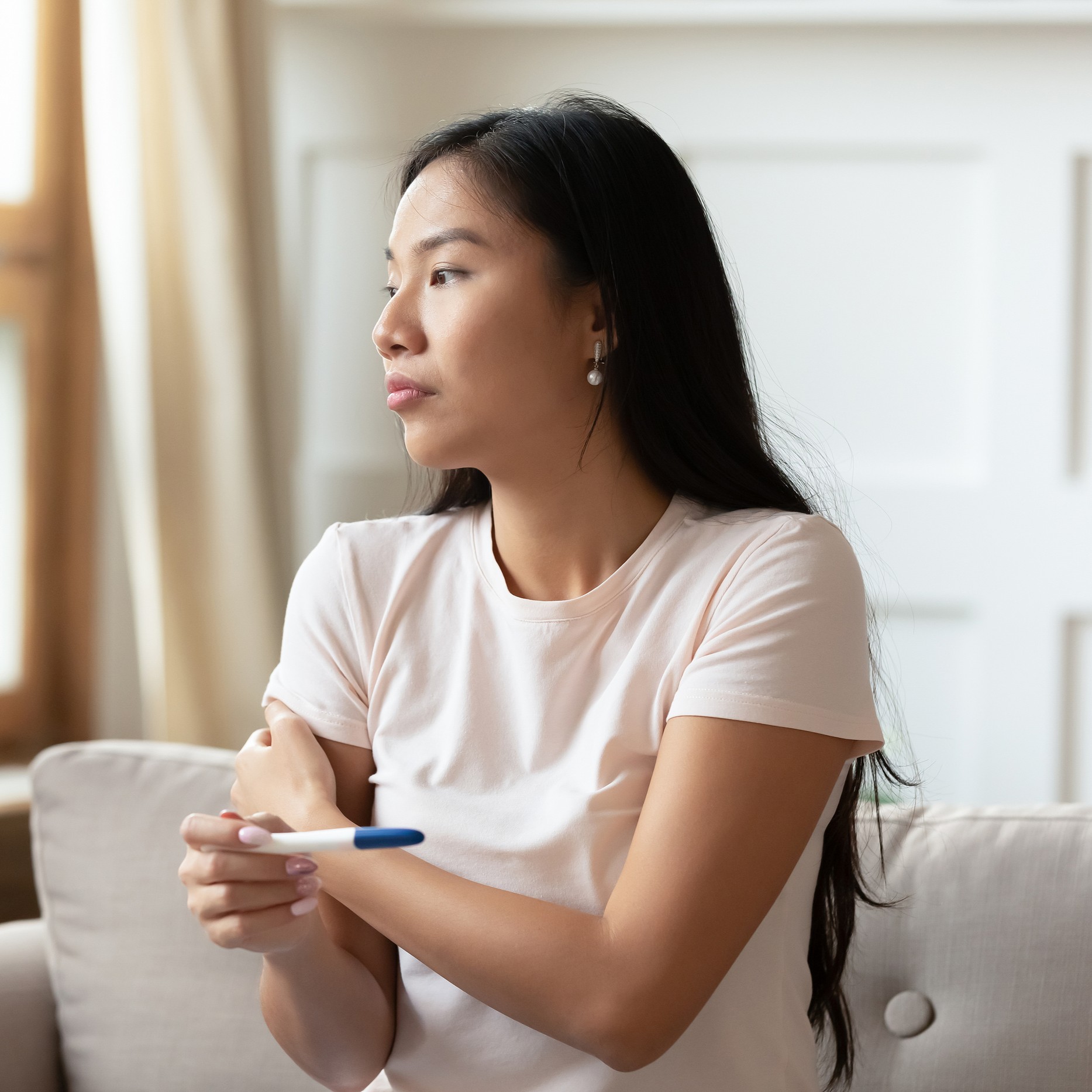 Pensive Asian Woman Do Ovulation Pregnancy Test